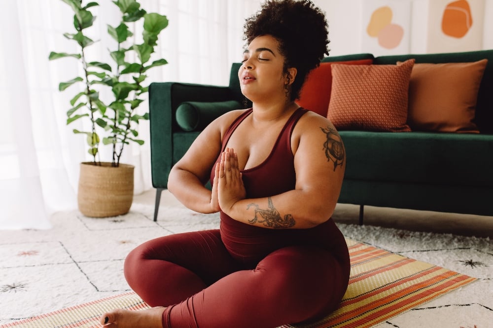 A woman with her eyes closed in a yoga pose in her home