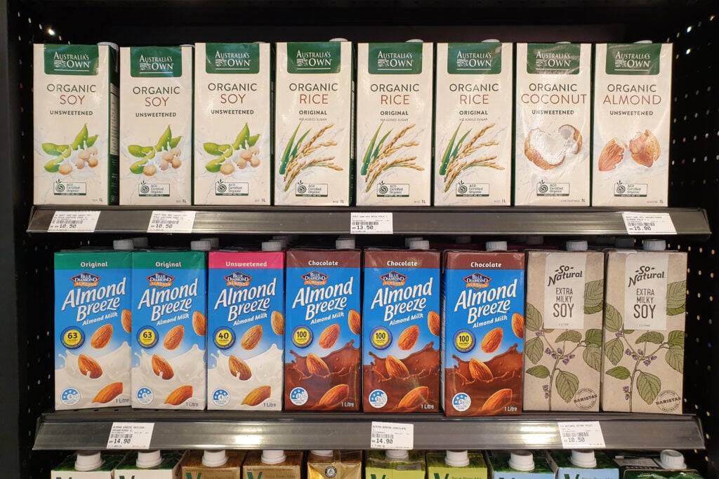 A row of plant-based milk cartons on a supermarket shelf