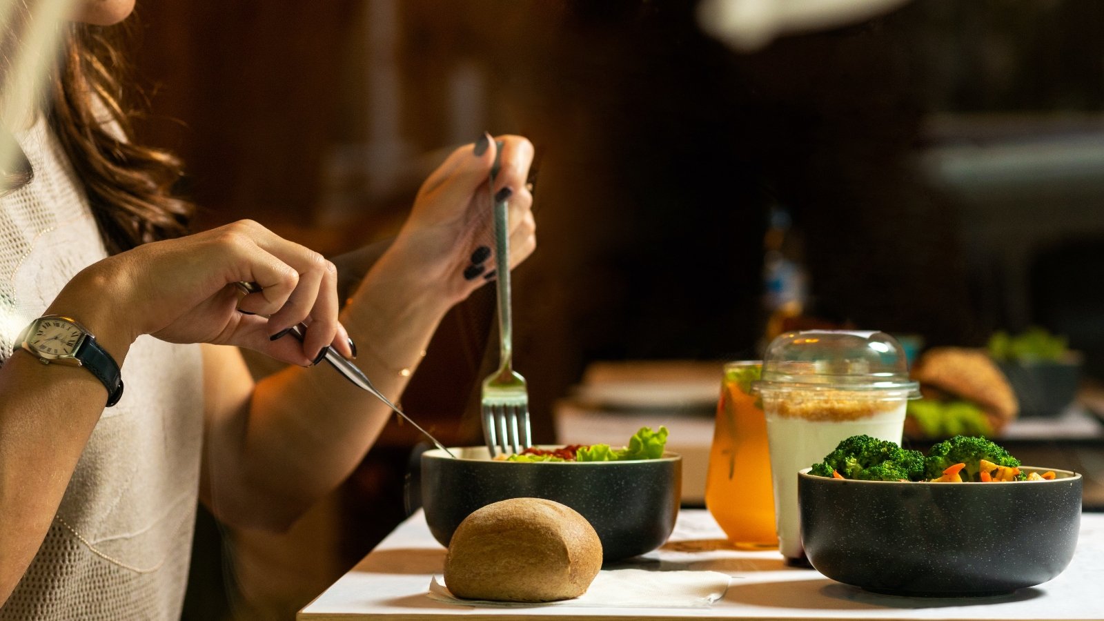 closeup shot of a woman eating salad with a knife and fork