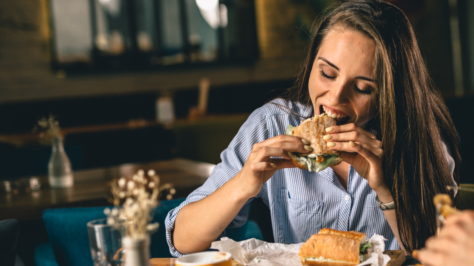 A woman eating a sandwich at a restaurant