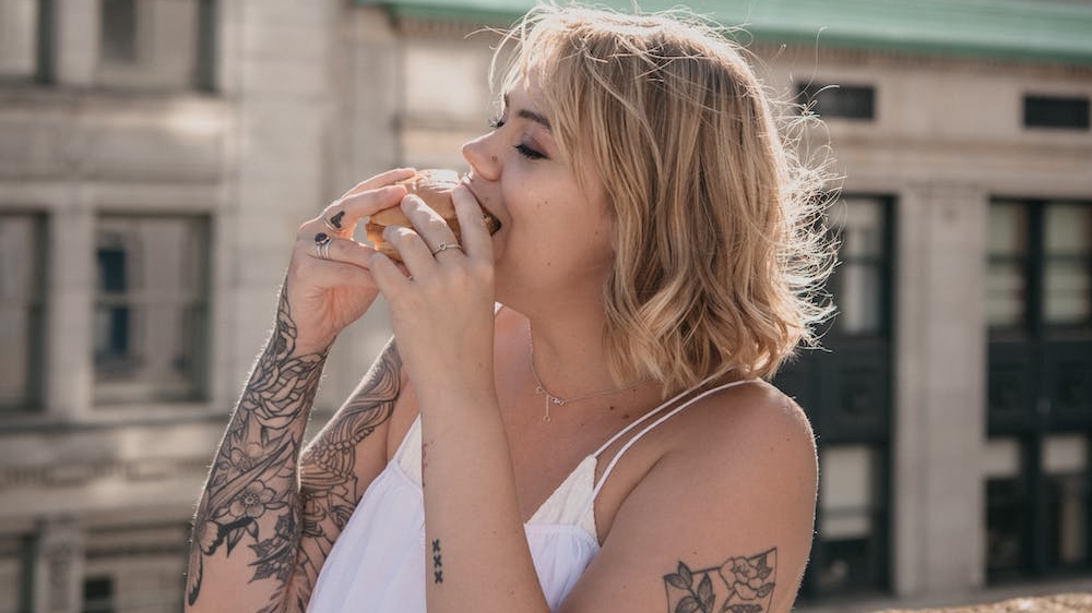 woman on a rooftop eating a burger