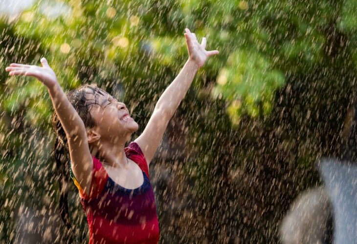 a child with their arms out in the rain