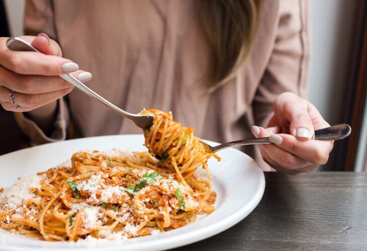 A woman twizzles spaghetti around a fork