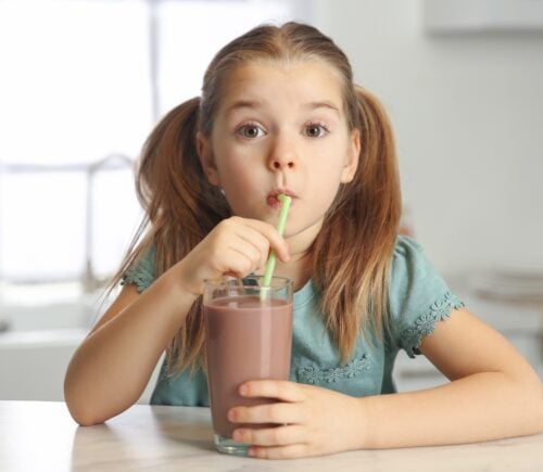 child drinking chocolate milk in the kitchen
