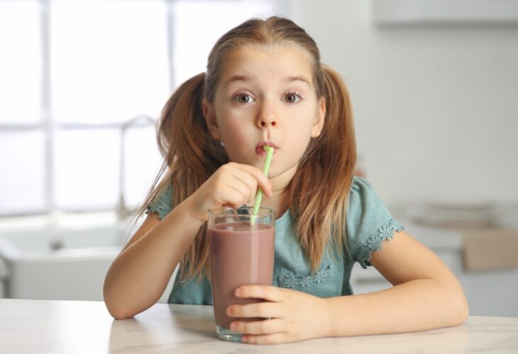 child drinking chocolate milk in the kitchen