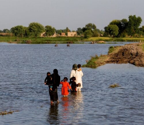 A family walks amid flood waters on their way to their village in Mehar, Pakistan