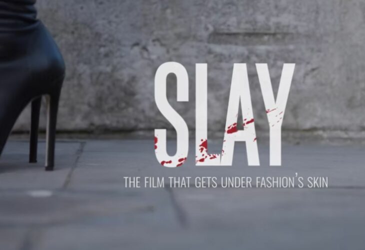 Black high heels on the pavement next to the words SLAY THE FILM THAT GETS UNDER FASHION'S SKIN