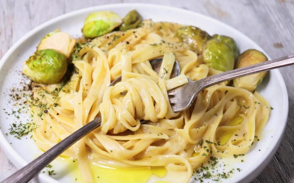 A plate of creamy and garlicky vegan Fettuccini Alfredo, with dairy-free butter and cashews