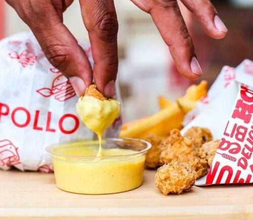 a person dips vegan fried chicken into sauce