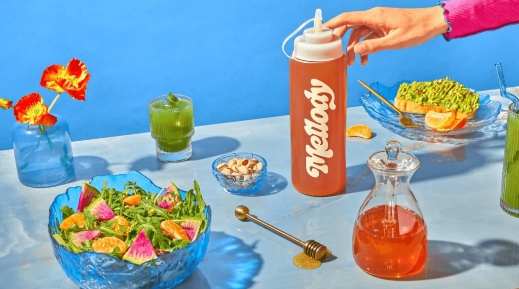 Art showing a bottle of vegan Mellody honey on a table with plant-based foods