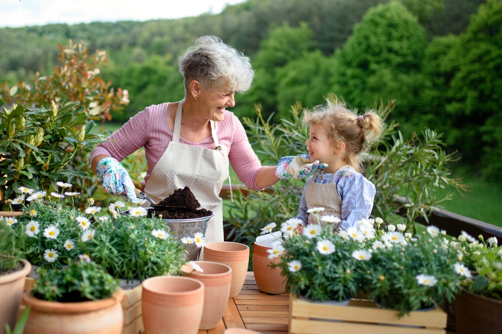 A senior woman and her granddaughter spend time outdoors potting plants