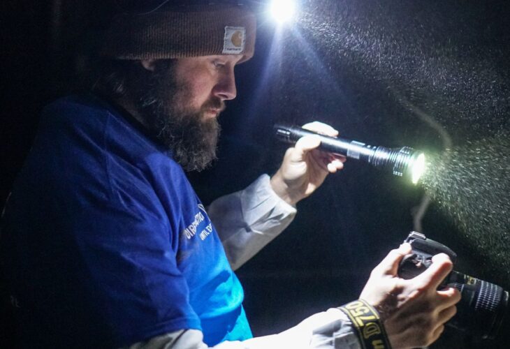 Animal activist Paul Darwin Picklesimer holding a camera in a factory farm
