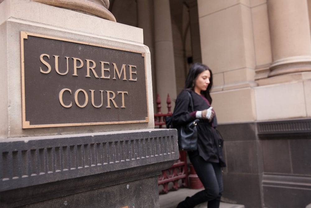 A woman walking past a supreme court plaque
