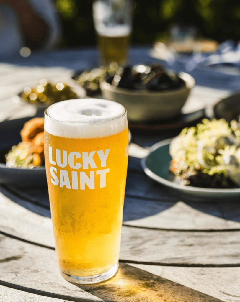 Vegan-friendly non-alcoholic beer in a glass reading Lucky Saint