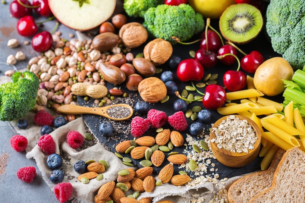 A selection of healthy, fiber- and protein-rich vegan foods like nuts, vegetables, and fruits