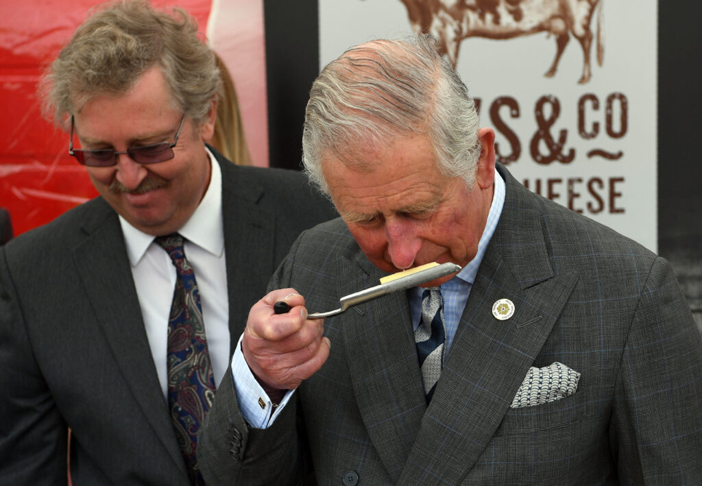 King Charles smells a piece of cheese, which is one of his favourite foods, on a royal visit