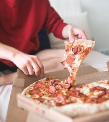 A person eating a pepperoni meat and dairy pizza