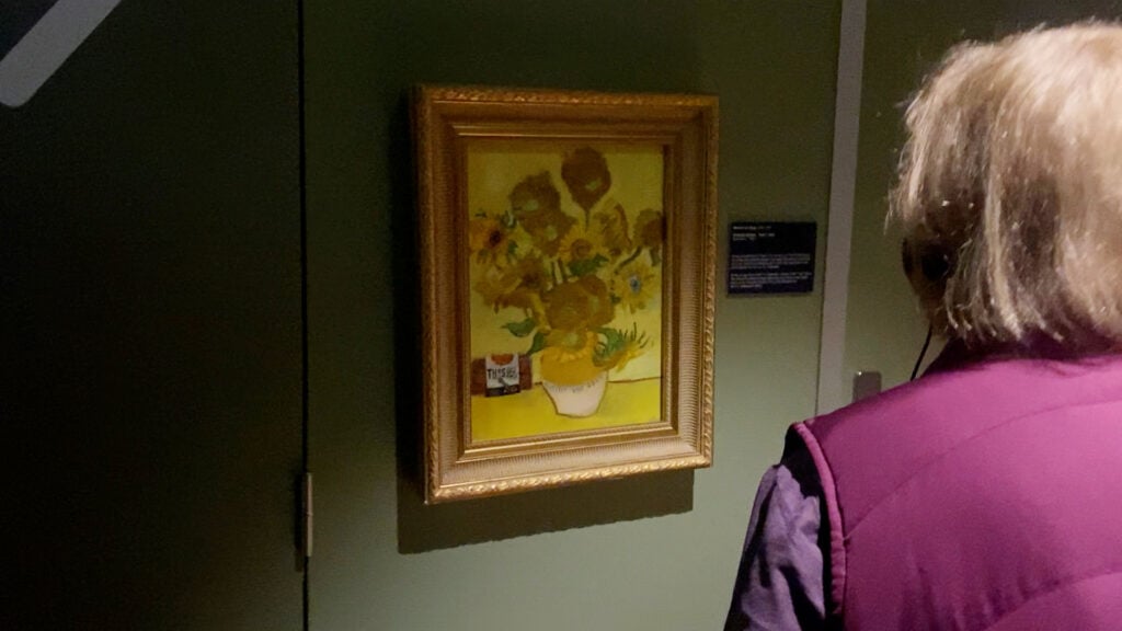 A visitor to the Van Gogh museum looks at the CE painting Sunflowers