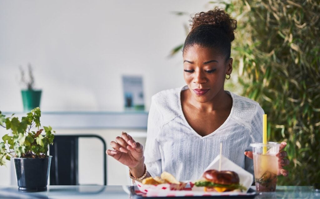 A woman wearing a white shirt sat at a table eating vegan food