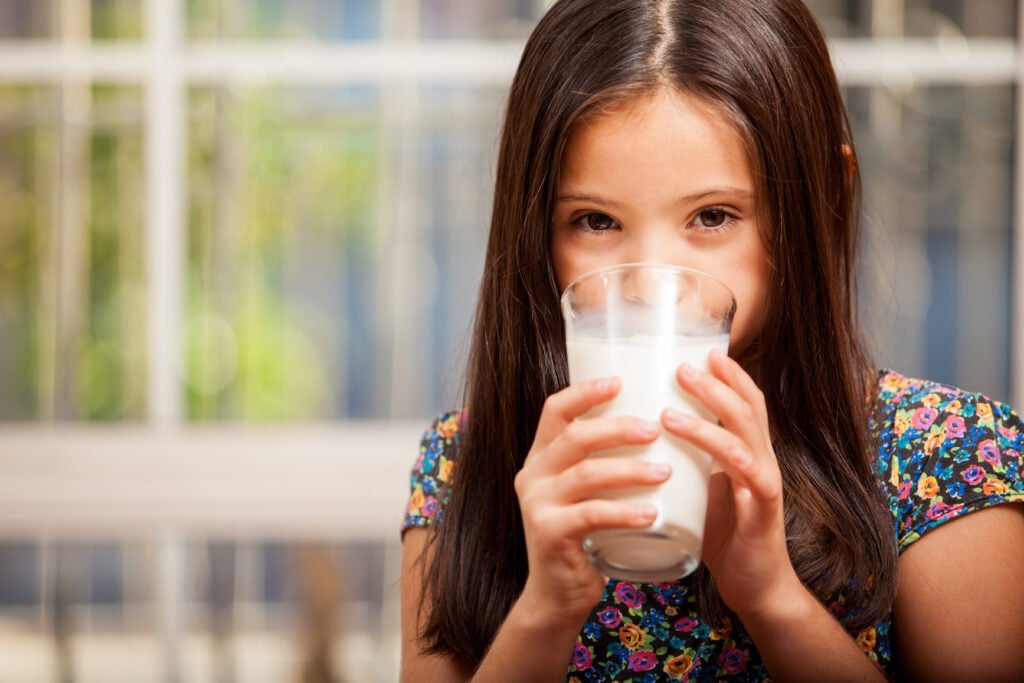 a child drinking a glass of dairy milk