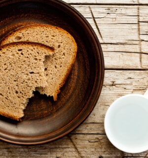 Two pieces of bread on a brown plate beside a white cup