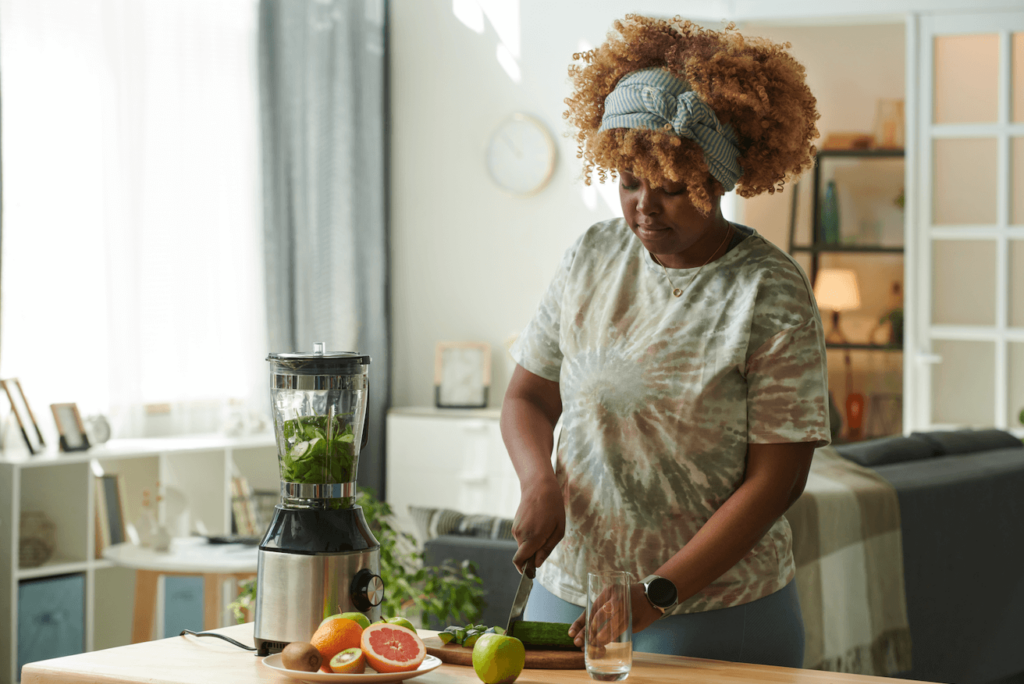 woman cutting vegetables for green smoothie at a table