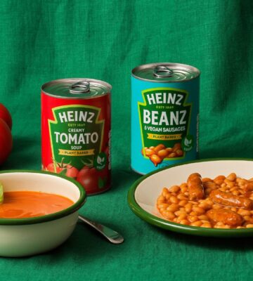 A can of Heinz vegan Cream Of Tomato soup besides a can of vegan sausages and beans