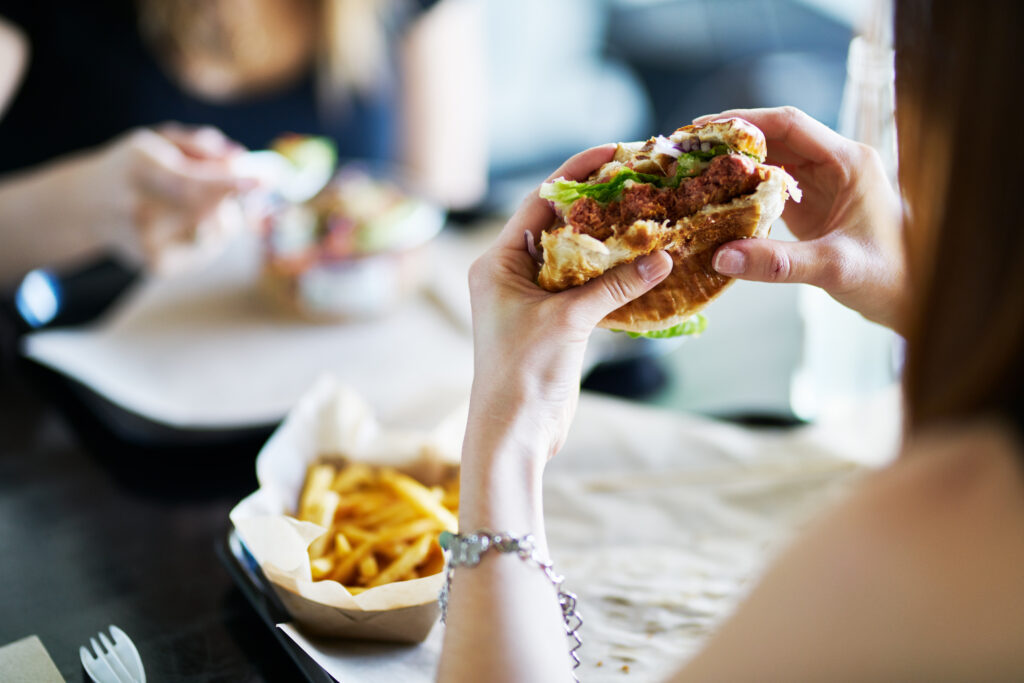 A woman eating a vegan burger and chips