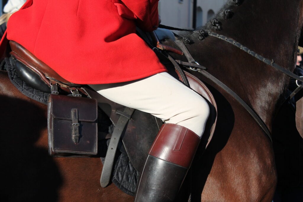 A fox hunter dressed in red riding a horse