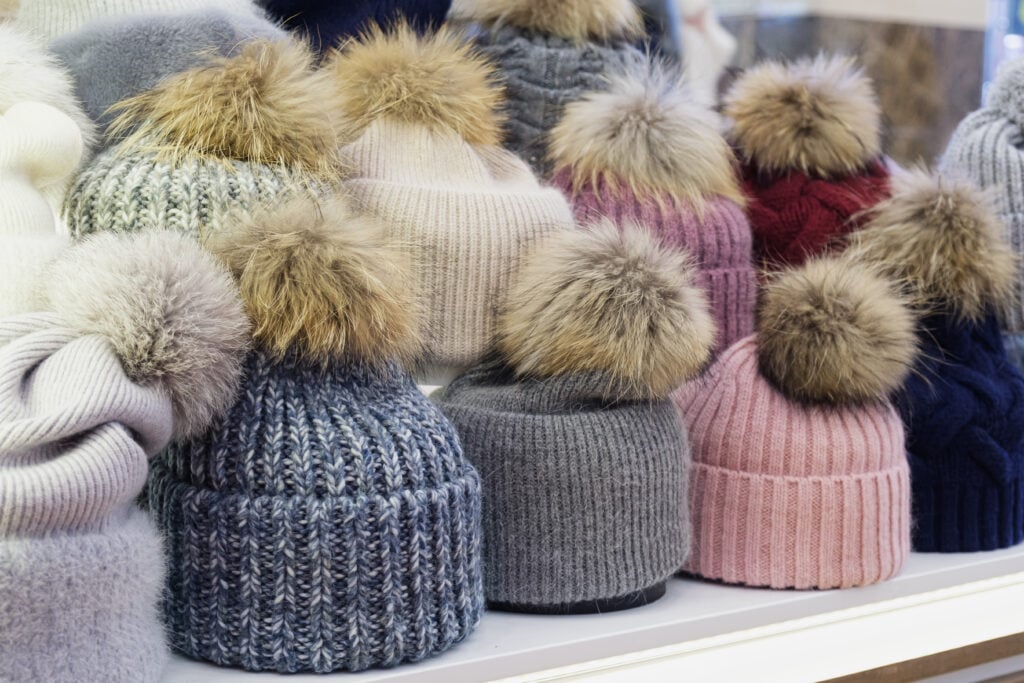 Hats with real fur pom poms on sale in a shop