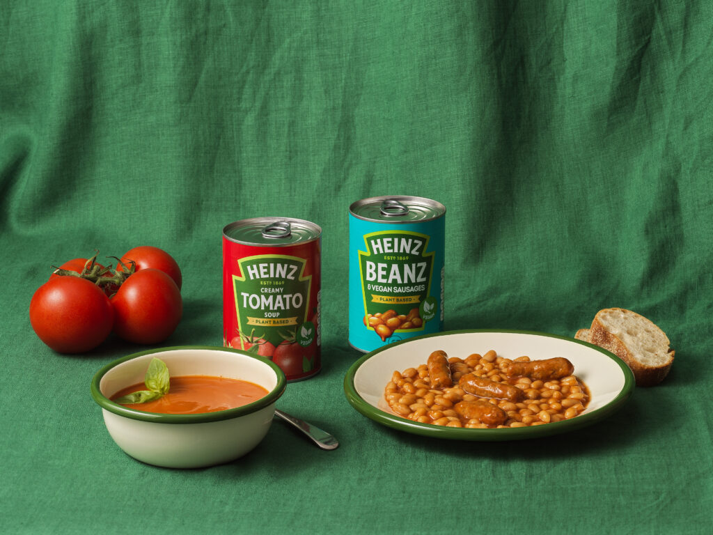 A can of Heinz Vegan Cream of Tomato Soup next to a can of Heinz Vegan Sausages and Beanz