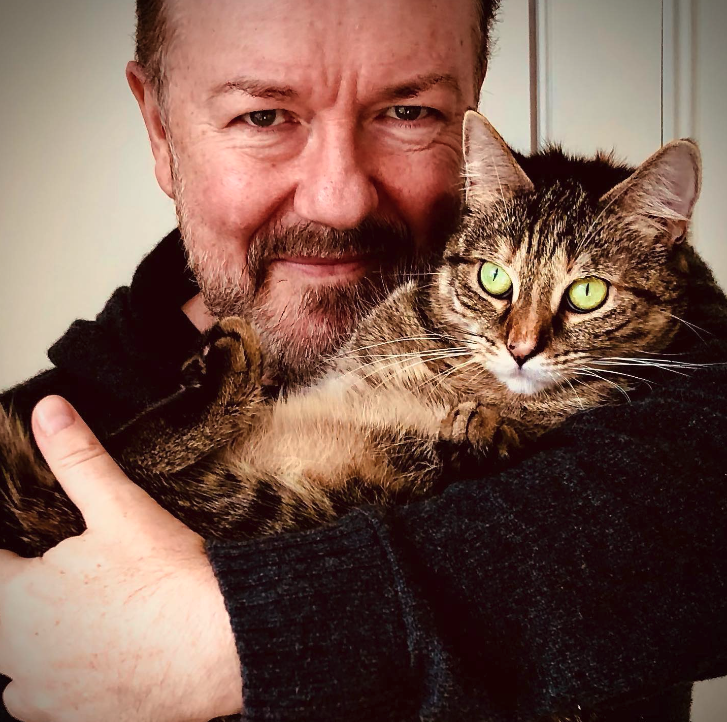 Vegan actor and comedian Ricky Gervais hugging his cat