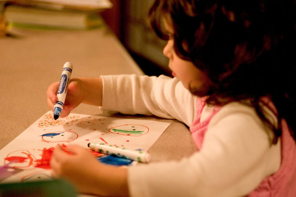 A child drawing a picture with Crayola markers