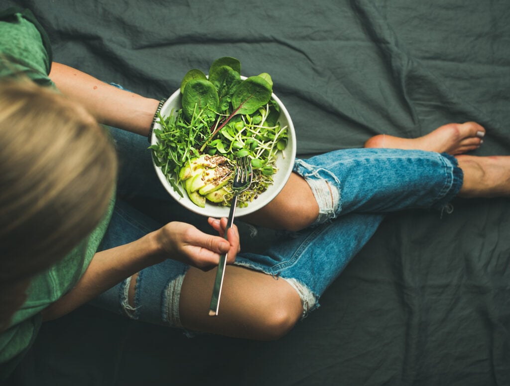 A woman eating a bowl of healthy vegan food