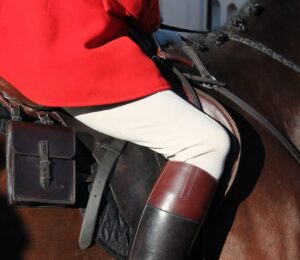 A UK fox hunter dressed in red uniform riding a horse