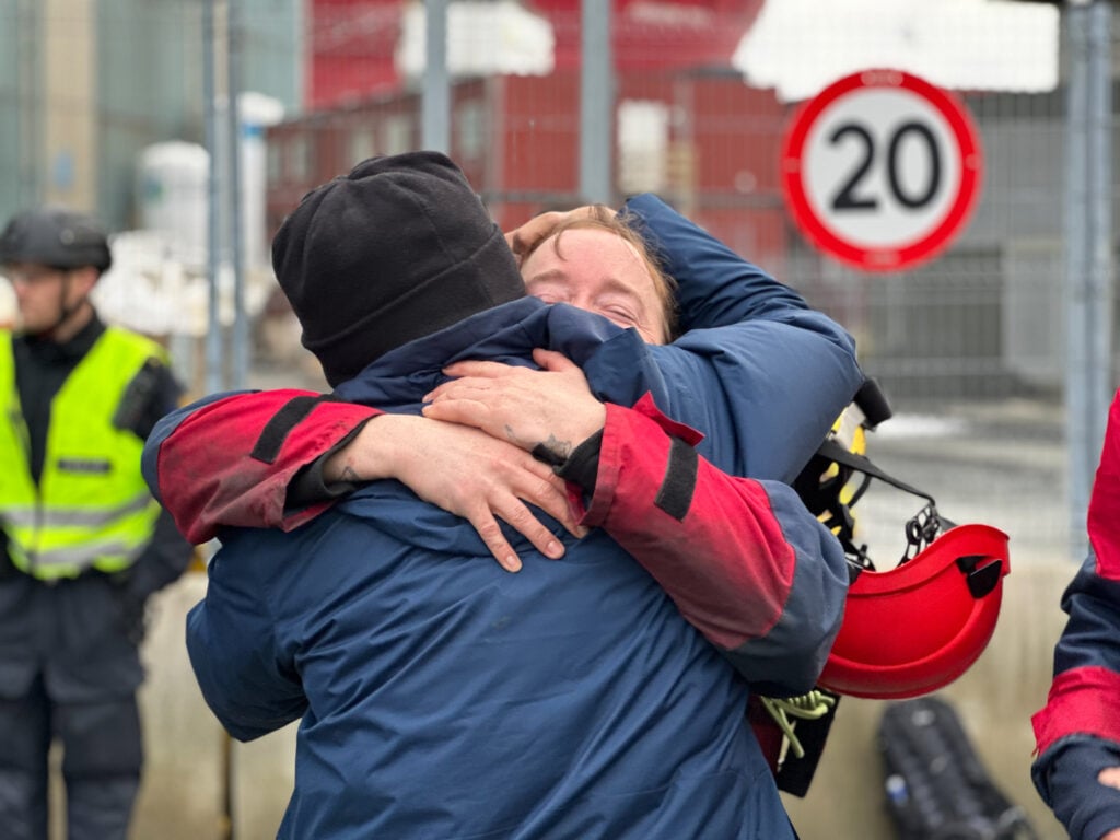 A Greenpeace activist hugs a friend after disembarking the Shell oil platform