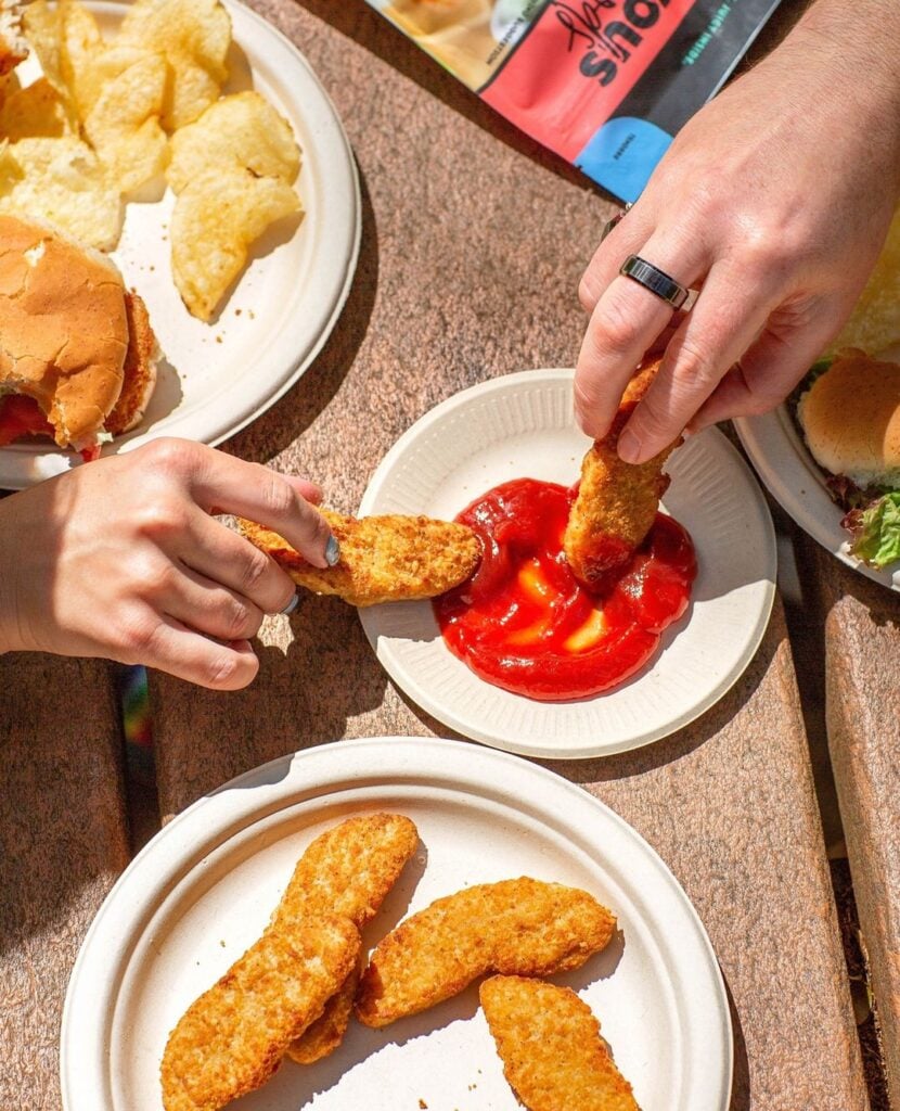 People dipping Rebellyous Foods' vegan chicken into sauce
