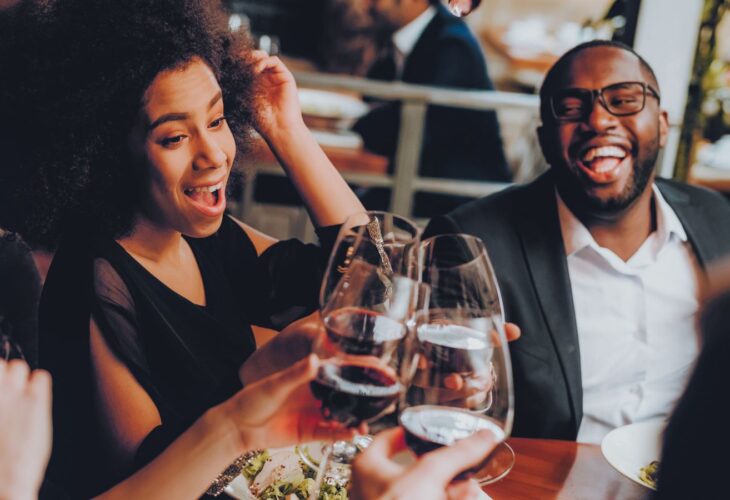 People looking happy and clinking their glasses together while eating vegan food at a US restaurant