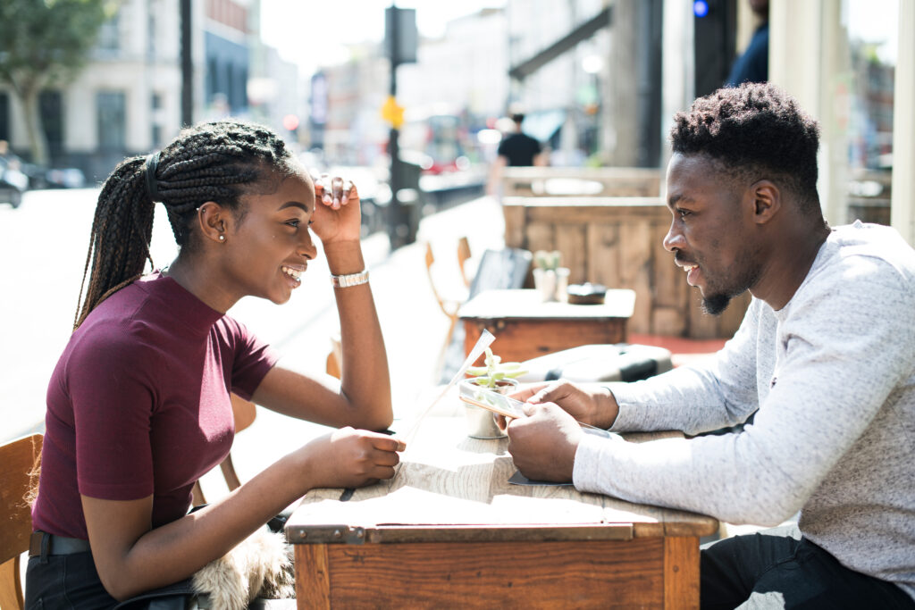 Two gen z people sitting outside ordering food at a restaurant