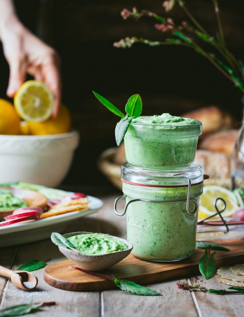 A jar of vegan hummus made from white kidney beans on a table with plant-based ingredients