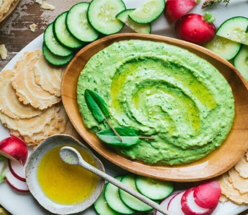 A spread of vegan hummus made from white kidney beans on a table with fresh plant-based ingredients