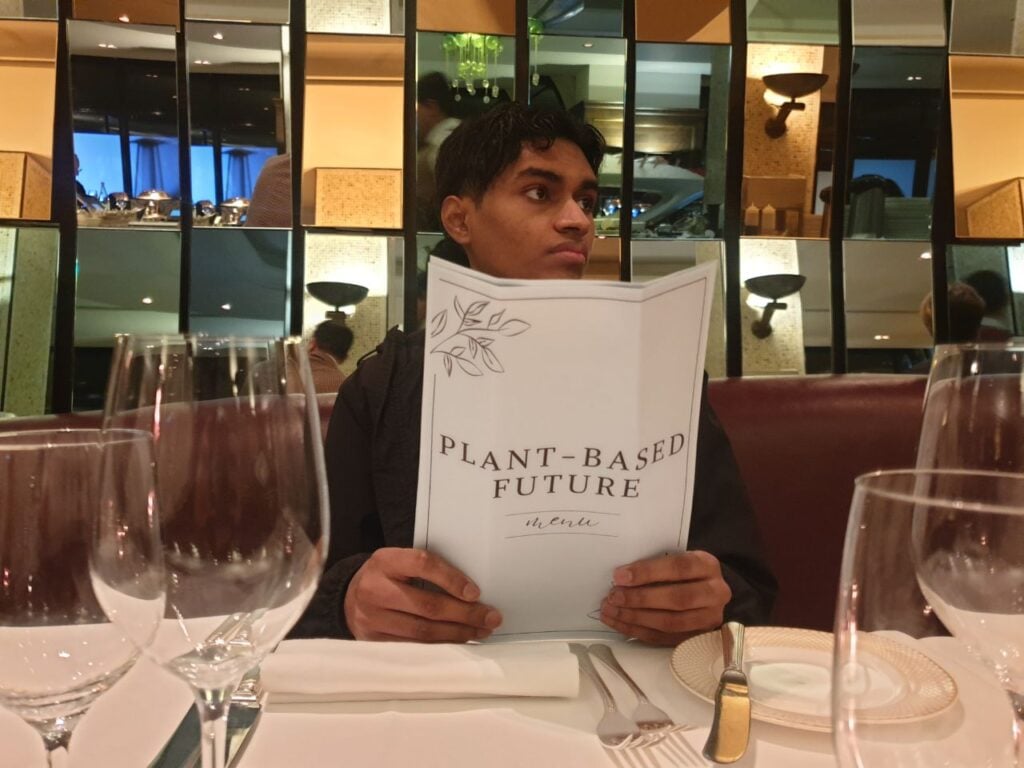 Animal Rebellion activist holding up a "menu" calling for a plant-based future at a seafood restaurant sit-in