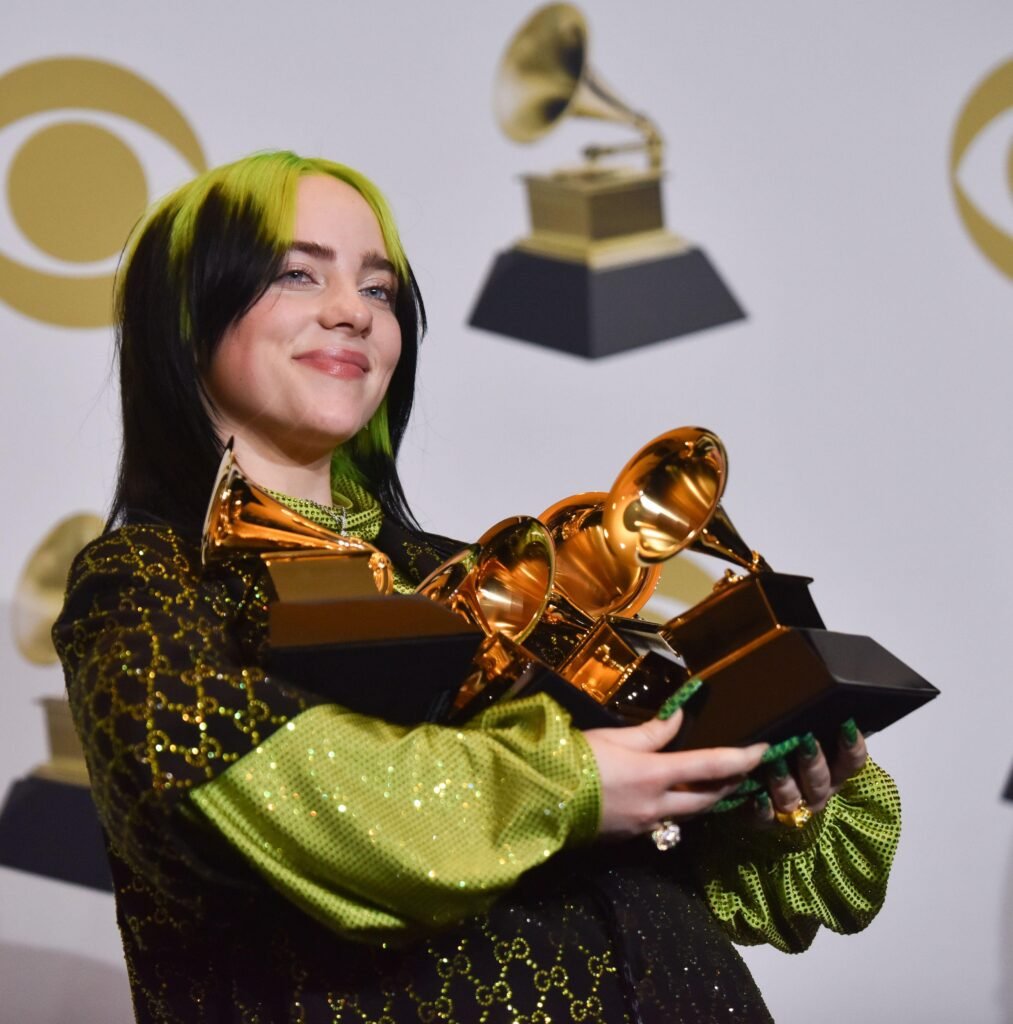 Vegan celebrity and singer-songwriter Billie Eilish on the red carpet holding multiple Grammy awards
