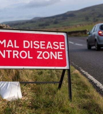A sign reading "animal disease control zone" by the side of a road in the UK