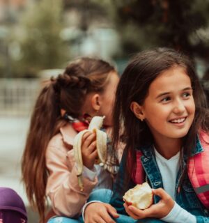 Children eating healthy plant-based food like fruit at a school