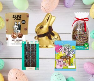 A range of vegan and dairy-free Easter chocolate and candy on a wooden plank backdrop, flanked by pastel Easter eggs