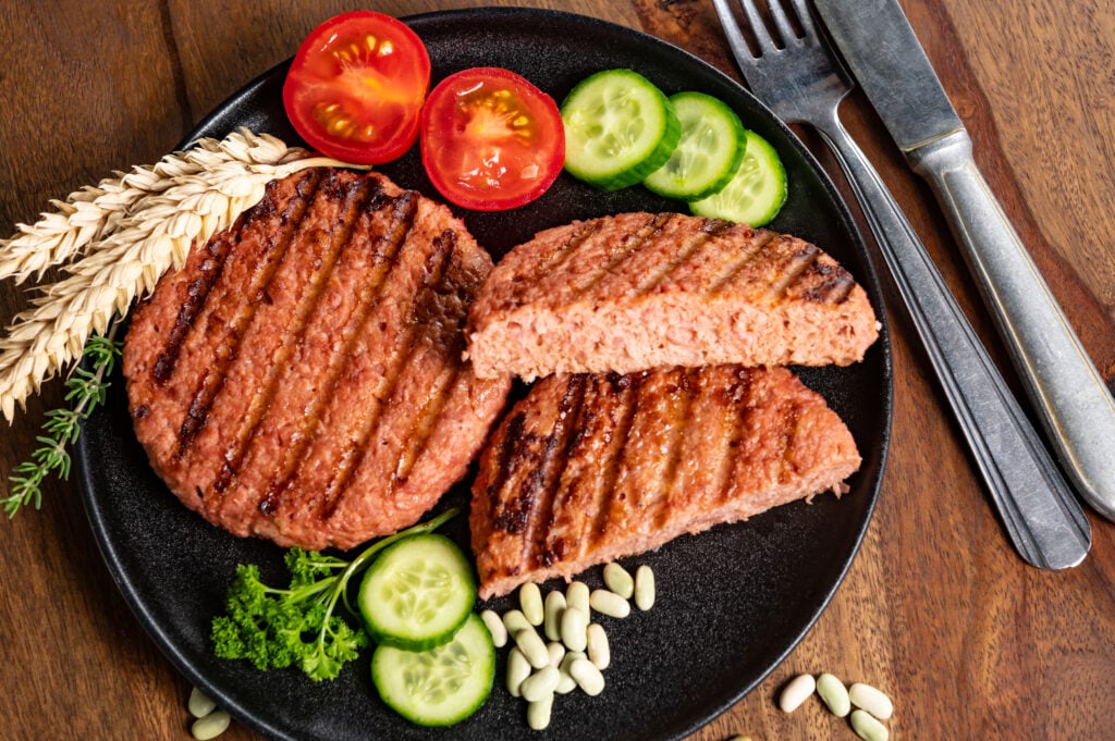 Plant-based burgers on a plate with tomatoes and cucumber