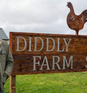 Jeremy Clarkson standing by a sign reading: "Diddly Squat Farm Shop"