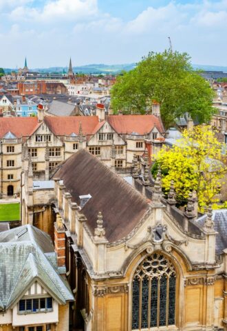 An aerial view of Oxford City, featuring old buildings and green trees