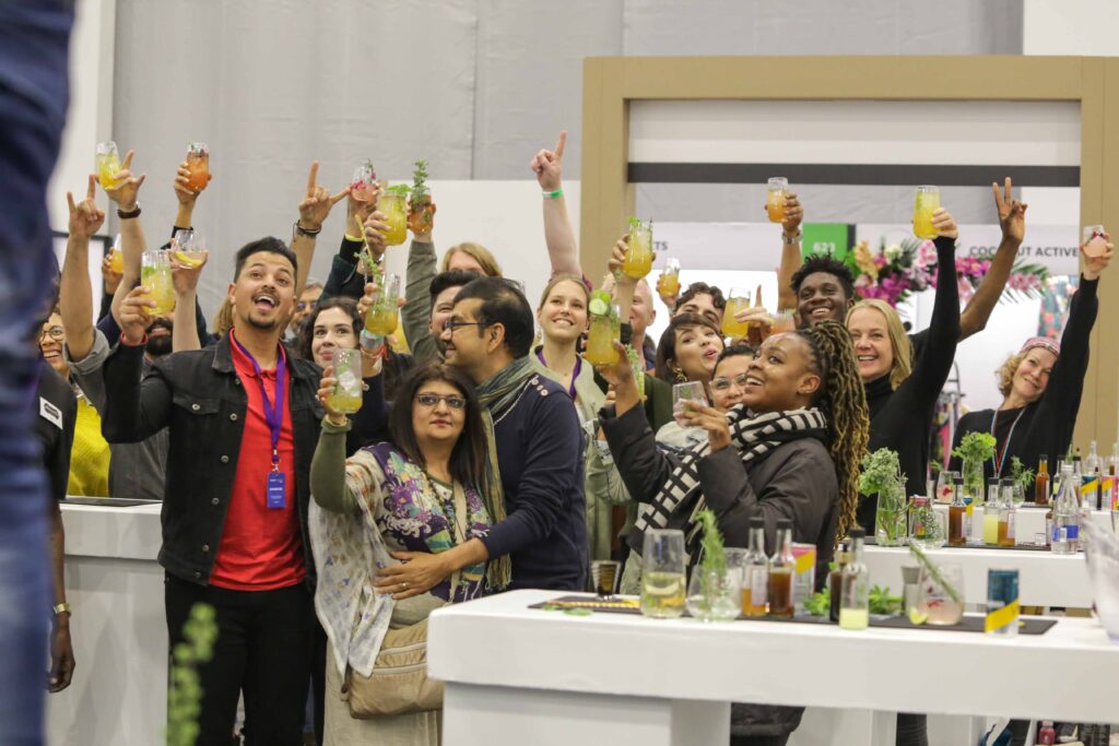 A group of people drink and celebrate while watching a live vegan cooking demonstration at the 2022 Plant Powered Show